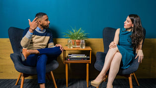  Seated man and woman and talking to each other in front of blue and wood wall | Style Standard