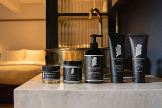  Men's Grooming Products on a bathroom counter with a bed in the background